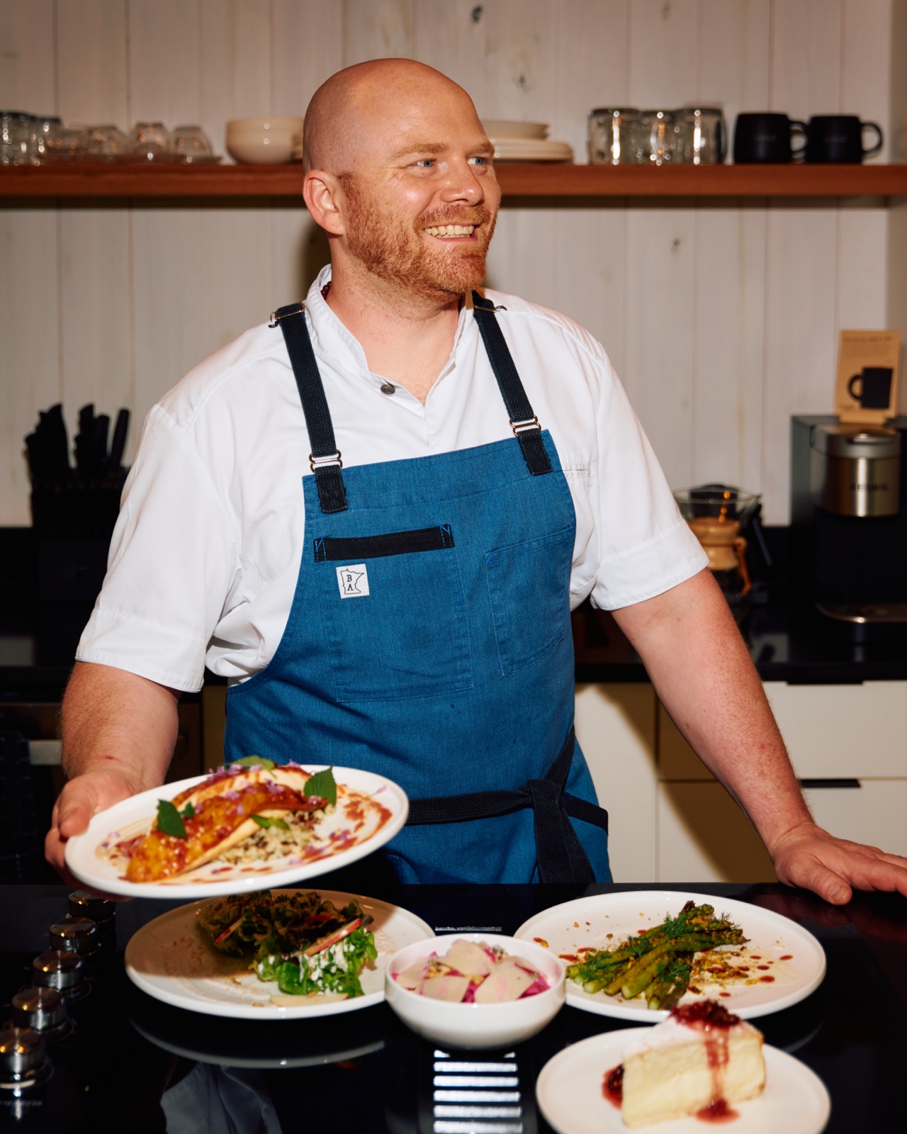 Chef John Lawrence with a spread of plated dishes in a Hugga kitchen